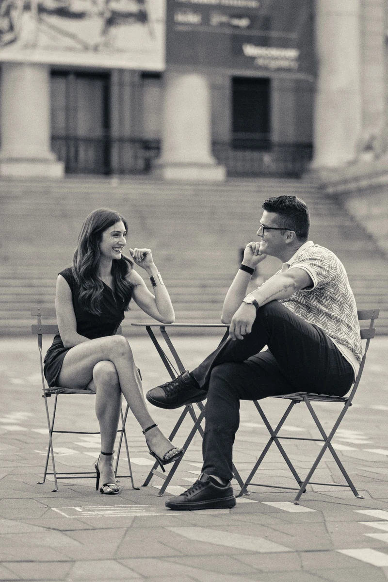 Kara and Nik smiling at each other at a cafe table